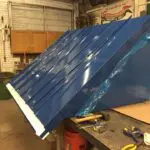 A blue metal roof being worked on in a shop.