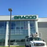 A truck parked in front of a building with the name bracco on it.