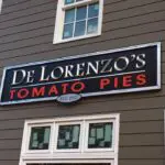 A sign for de lorenzo 's tomato pies on the side of a building.