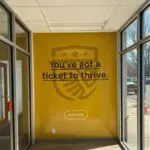A yellow wall with a sticker that says " you 've got a ticket to thrive ".